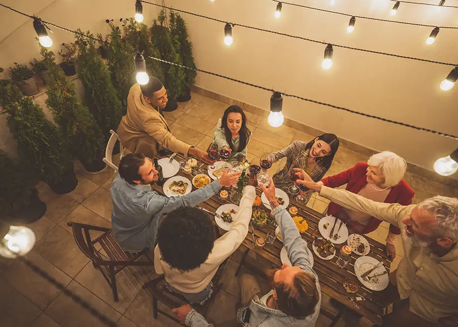 diverse ground of friends, family gathered on concrete patio for a meal outdoors, making a toast, cheers - Collinsville, IL