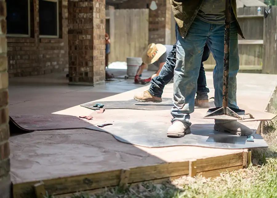 professional workers applying stamps to fresh poured concrete patio, creating natural stone effect - Collinsville, IL