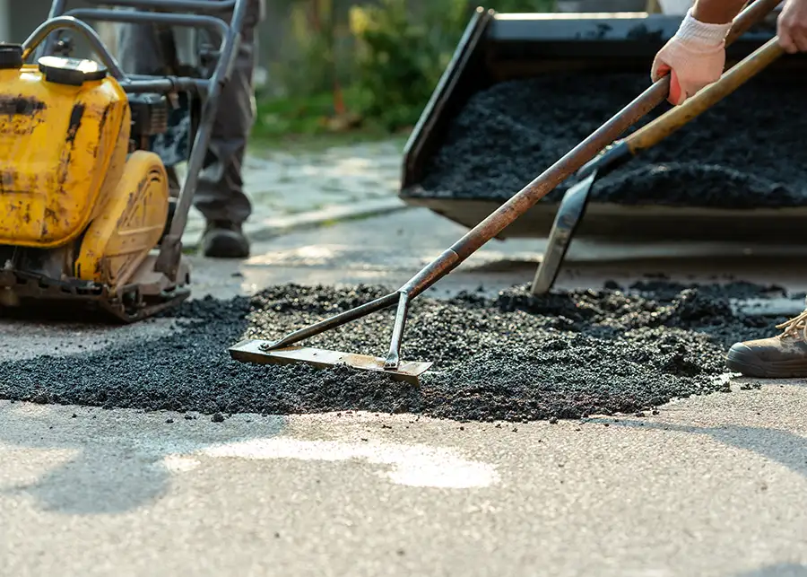 hot patch asphalt, pothole repair, professionals tamping down fresh asphalt patch - Collinsville, IL